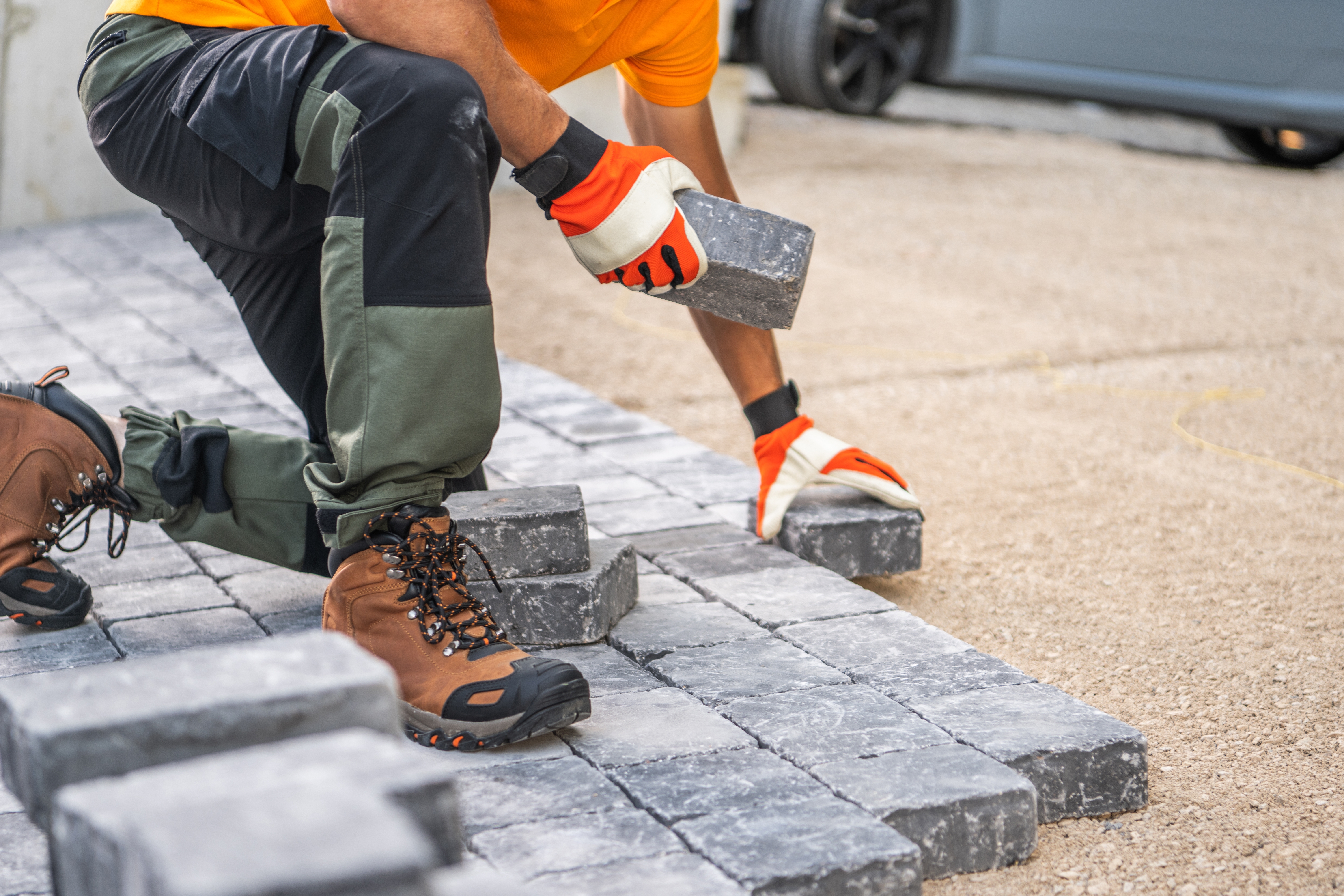 Worker laying pavers by hand
