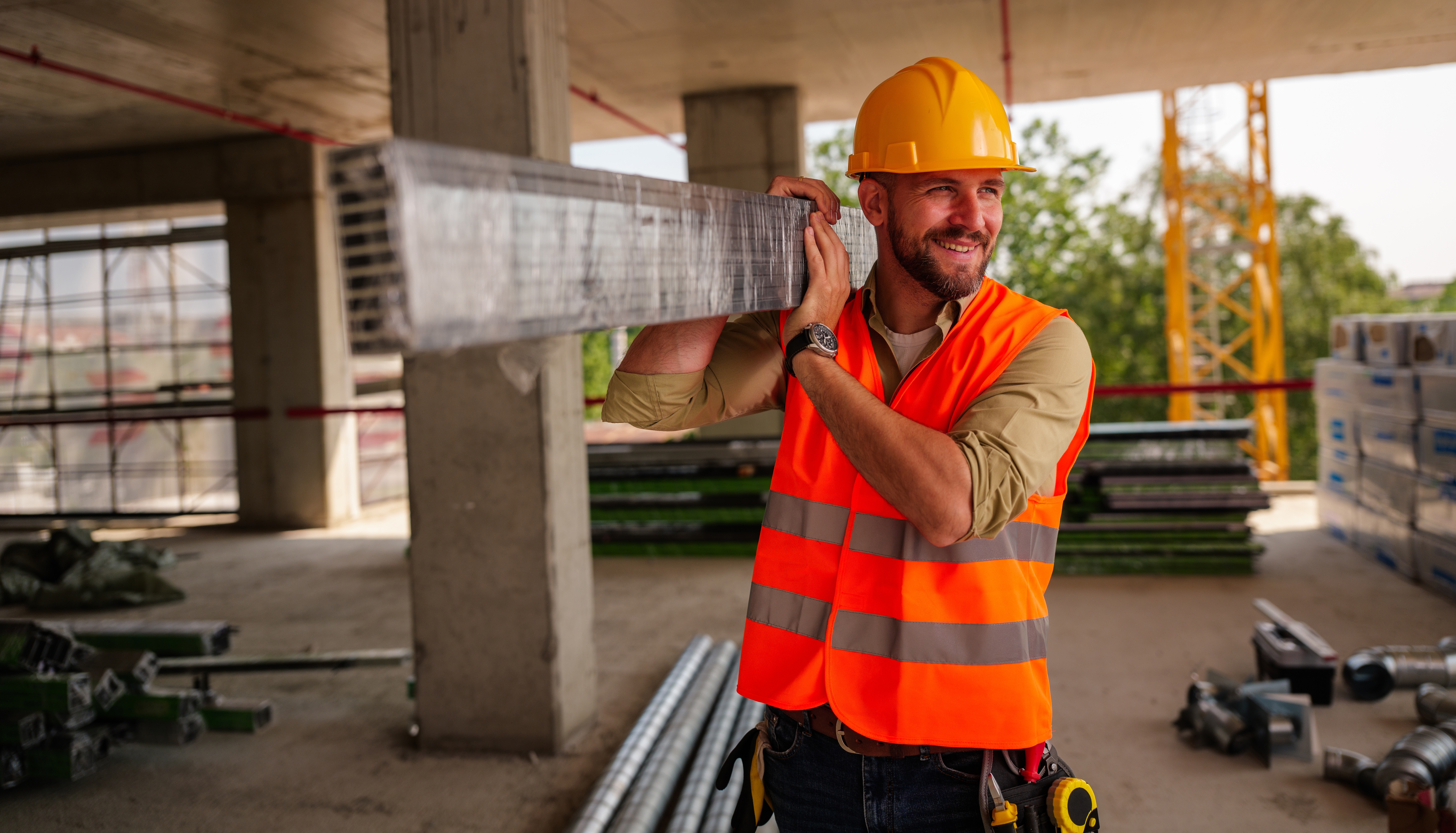 Construction worker carrying steel beam on site